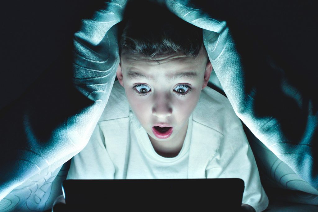 storytelling - pojke tittar på ipad under täcket